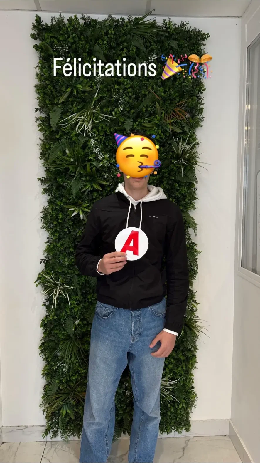Élève avec son disque A devant le mur végétal de l'agence